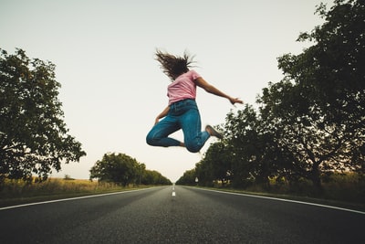 粉色的上衣和蓝色的裤子的女人跳上道路行驶
